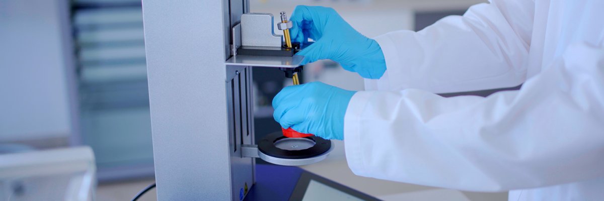TOPITEC Header 1 Eine Apothekerin in blauen Handschuhen zeigt, wie man den Topitec benutzt.