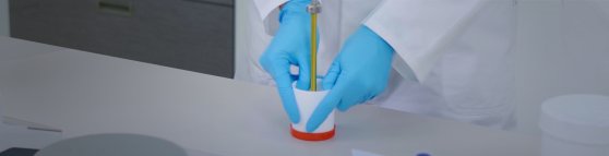 Eine Apothekerin in blauen Handschuhen zeigt, wie man den Topitec benutzt.