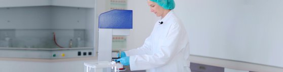 Eine Apothekerin in blauen Handschuhen zeigt, wie man den Topitec benutzt.